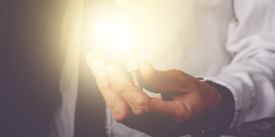 Business idea and vision businessman holding light bulb concept of new ideas innovation invention and creativity retro toned image selective focus.
